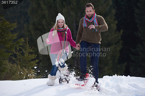 Image of couple having fun and walking in snow shoes