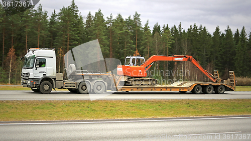 Image of White Mercedes-Benz Truck hauls Hitachi Excavator on Motorway