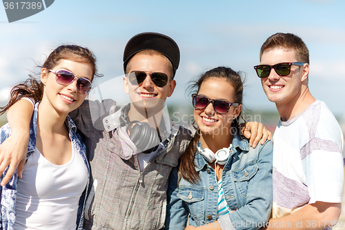 Image of smiling teenagers in sunglasses hanging outside