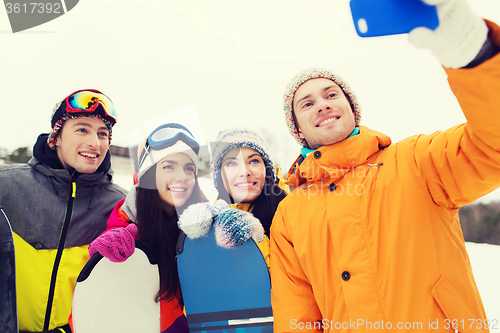 Image of happy friends with snowboards and smartphone