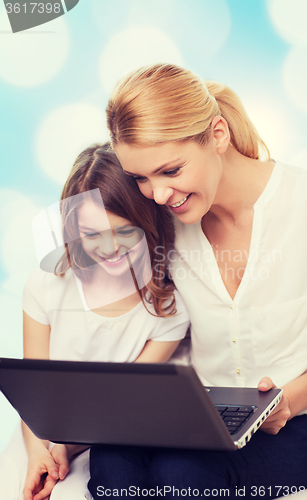 Image of smiling mother and little girl with laptop