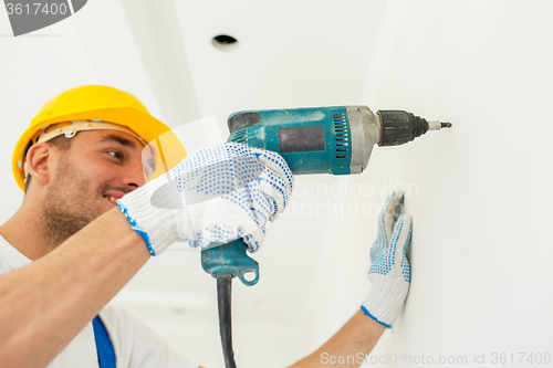 Image of builder in hardhat with drill perforating wall