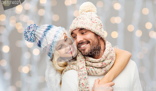 Image of happy couple in winter clothes hugging over lights