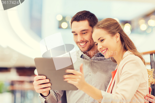 Image of happy couple with tablet pc taking selfie in mall