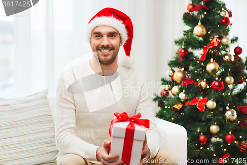 Image of happy man with christmas gift box at home