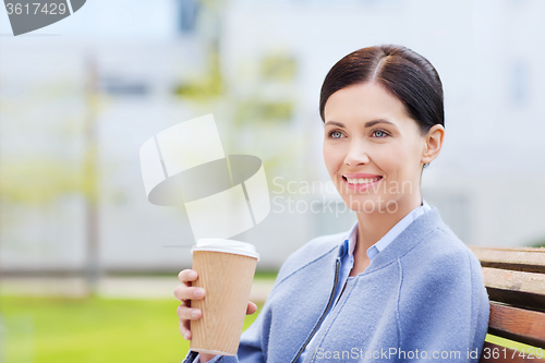 Image of smiling woman drinking coffee outdoors