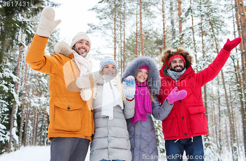 Image of group of friends waving hands in winter forest