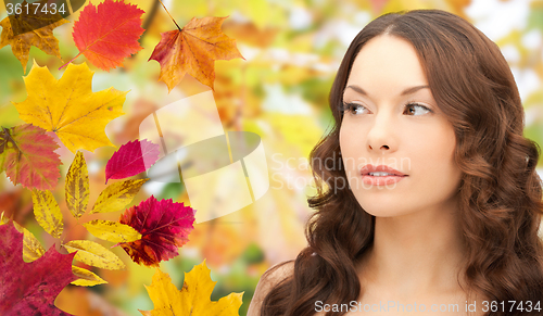 Image of beautiful young woman face over autumn leaves