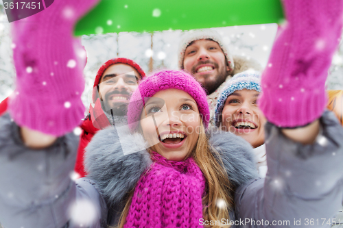 Image of smiling friends with tablet pc in winter forest