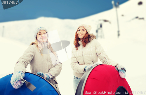 Image of happy girl friends with snow tubes outdoors