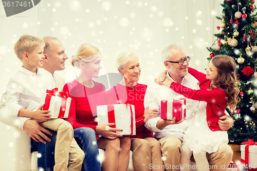 Image of smiling family with gifts hugging at home