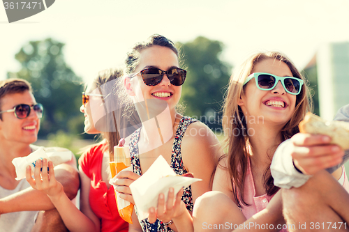 Image of group of smiling friends sitting on city square