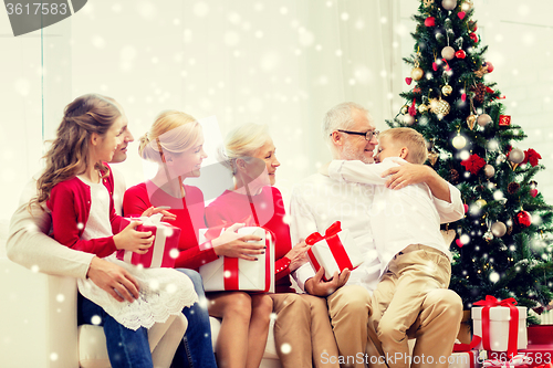 Image of smiling family with gifts hugging at home