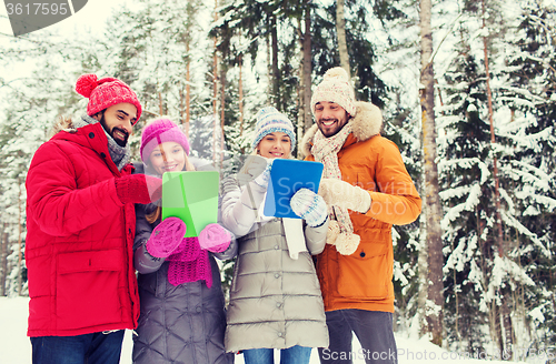 Image of smiling friends with tablet pc in winter forest
