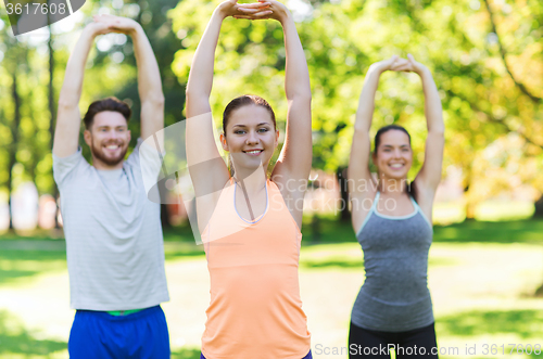 Image of group of friends or sportsmen exercising outdoors