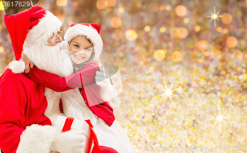 Image of smiling girl cuddling with santa claus over lights