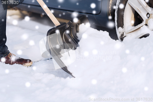 Image of closeup of man digging snow with shovel near car