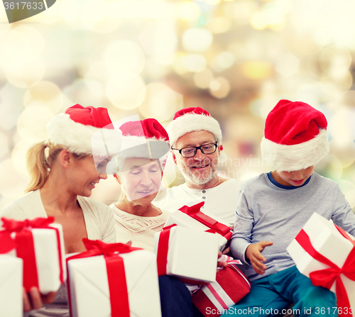 Image of happy family in santa helper hats with gift boxes