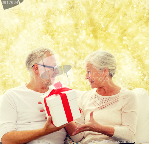 Image of happy senior couple with gift box at home