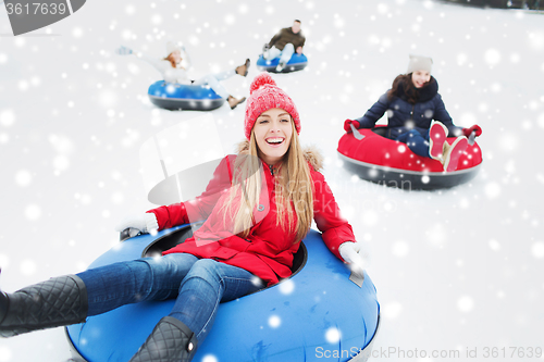 Image of group of happy friends sliding down on snow tubes