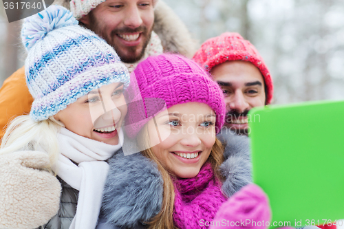 Image of smiling friends with tablet pc in winter forest
