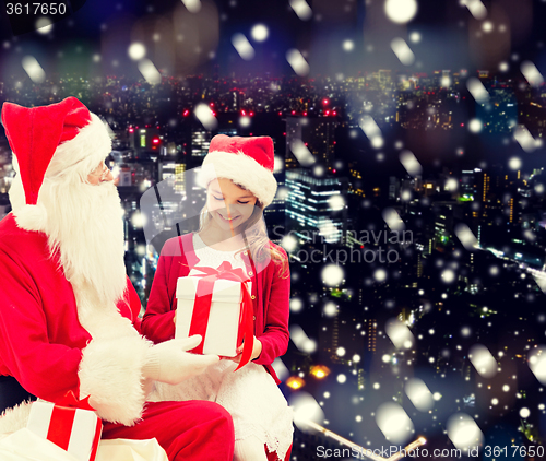 Image of smiling little girl with santa claus and gifts