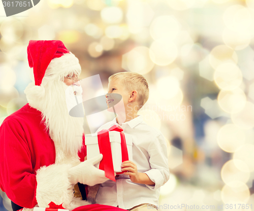 Image of smiling little boy with santa claus and gifts