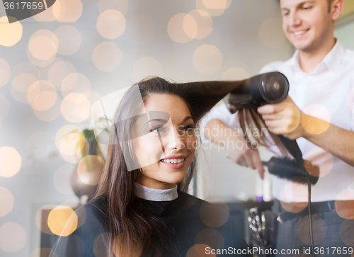 Image of happy woman with stylist making hairdo at salon