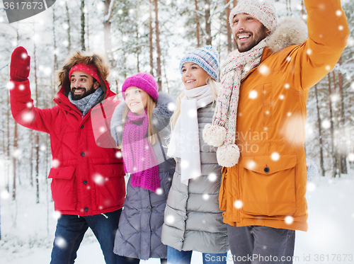 Image of group of friends waving hands in winter forest