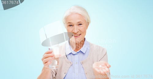 Image of happy senior woman with water and medicine