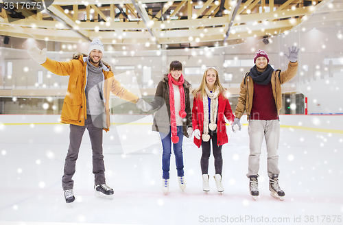 Image of happy friends waving hands on skating rink