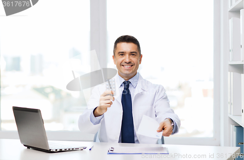 Image of smiling doctor with tablets and laptop in office