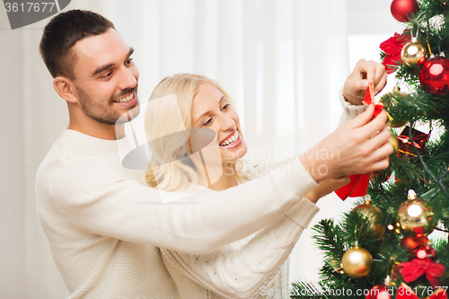 Image of happy couple decorating christmas tree at home
