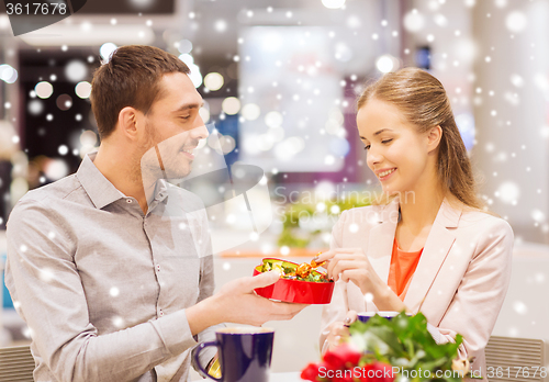 Image of happy couple with present and flowers in mall