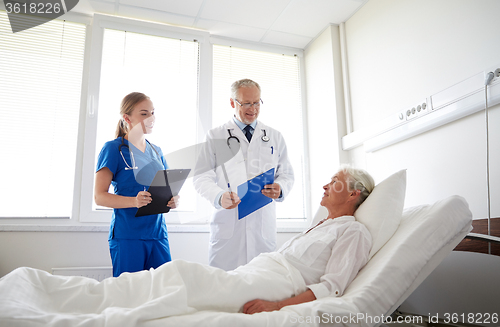 Image of doctor and nurse visiting senior woman at hospital