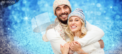 Image of happy couple in winter clothes hugging over lights