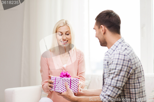 Image of happy man giving woman gift box at home