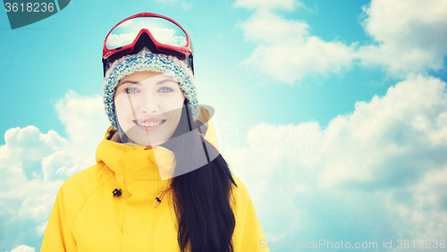 Image of happy young woman in ski goggles over blue sky