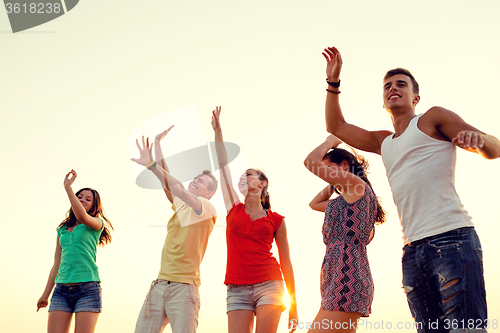 Image of smiling friends dancing on summer beach