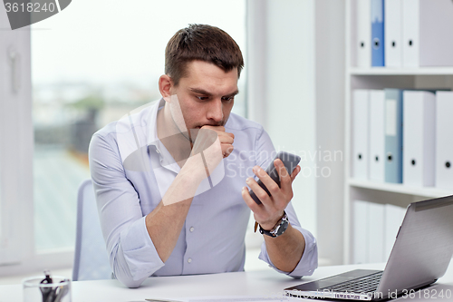 Image of businessman with smartphone and laptop at office