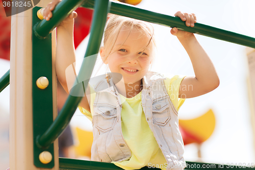 Image of happy little girl climbing on children playground