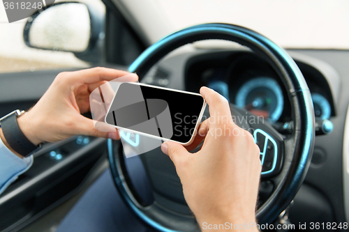 Image of close up of man hand with smartphone driving car