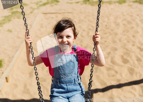 Image of happy little girl swinging on swing at playground