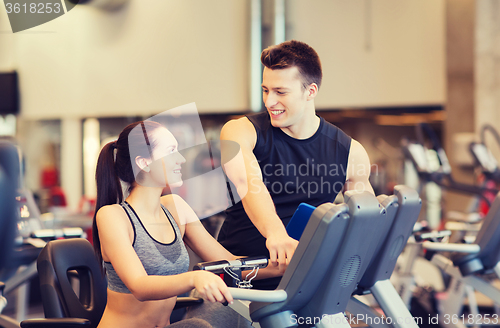 Image of happy woman with trainer on exercise bike in gym