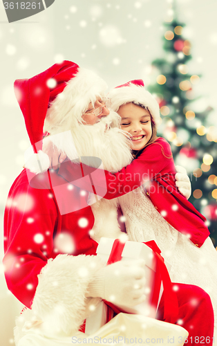 Image of smiling girl with santa claus and gift at home