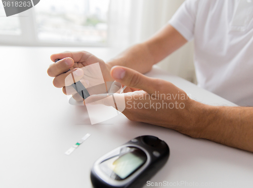 Image of close up of man checking blood sugar by glucometer