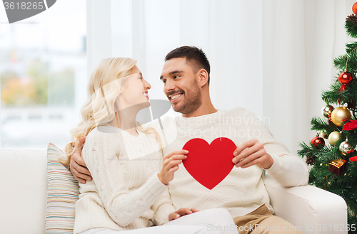 Image of happy couple with red heart at home for christmas