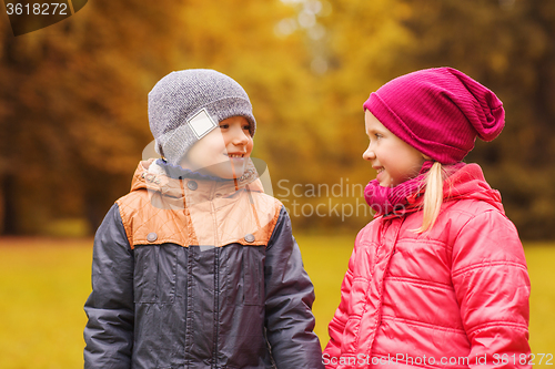 Image of happy little girl and boy talking in autumn park