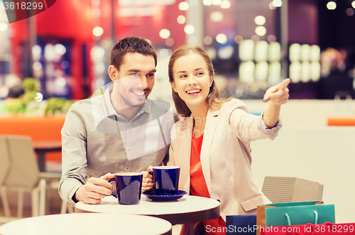 Image of happy couple with shopping bags drinking coffee