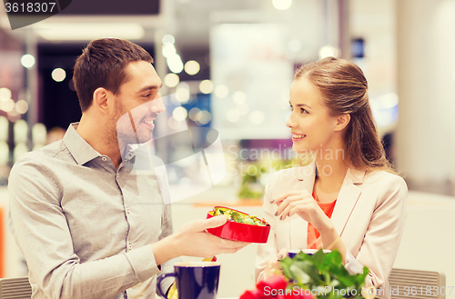 Image of happy couple with present and flowers in mall